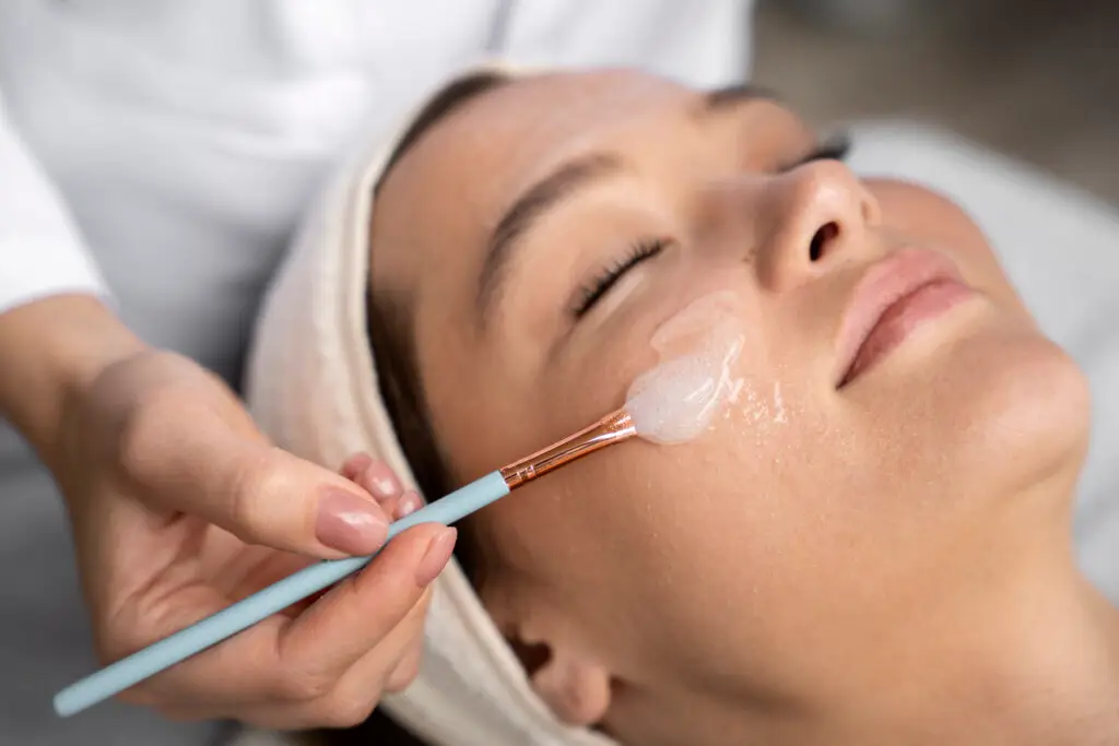 Aplicação de máscara facial em procedimento dermatológico, reforçando cuidado estético e atenção à saúde da pele