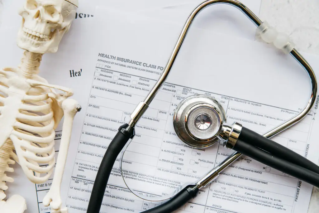 Estetoscópio sobre documentos médicos e modelo anatômico, representando avaliação clínica e organização no atendimento.