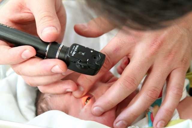 Exame pediátrico do ouvido com otoscópio, avaliando a saúde auditiva e possíveis infecções no bebê.